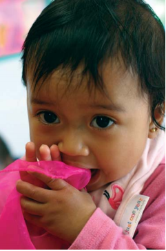 A child chewing on a pink blanket.