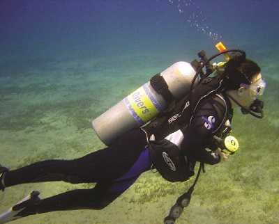 This photograph shows a scuba diver underwater with a tank on his or her back and bubbles ascending from the breathing apparatus.