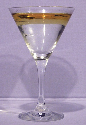 This is a photo of a clear, colorless martini glass containing a golden colored liquid layer resting on top of a clear, colorless liquid.